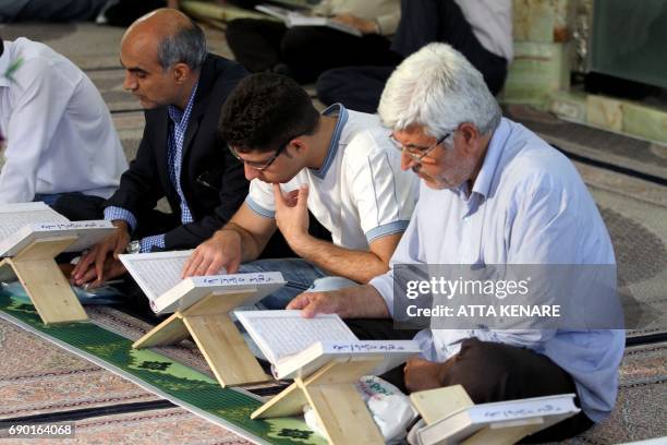 Shiite Muslims read the Koran prior to breaking fast at Emamzadeh Saleh mosque in Tajrish square in northern Tehran on May 30 during the holy fasting...