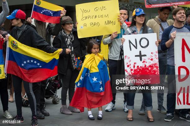 Little girl is wrapped in the Venezuelan flag while activists hold signs during a protest against Goldman Sach's bond purchase transaction of $2.8...
