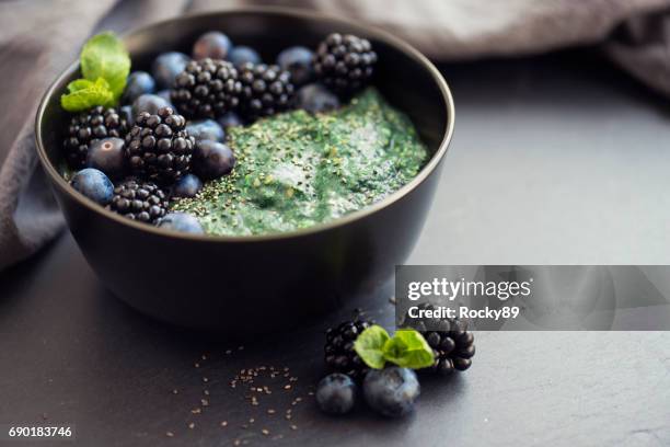 gesunde bio spirulina brei mit beeren garniert - blue bowl stock-fotos und bilder