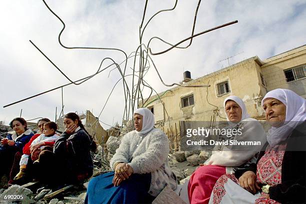 Members of the Khalil family sit on the ruins of their home after Jerusalem municipal workers demolished the newly-built structure January 14, 2002...