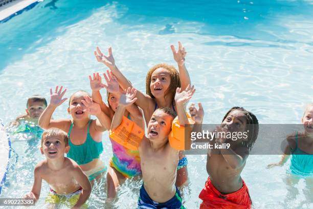 multi-ethnic group of children playing in swimming pool - kids pool games stock pictures, royalty-free photos & images