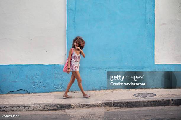 壁に歩道を離れて幸せな女 - cuba ストックフォトと画像