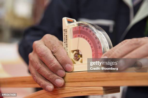 Member of a Nitori Holdings Co. Quality control team measures an angle on a chair during a product test in Tokyo, Japan, on Tuesday, April 25, 2017....