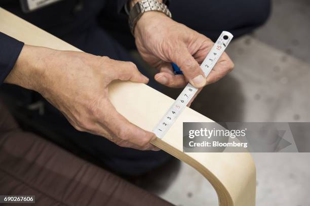 Members of a Nitori Holdings Co. Quality control team measures the width of a chair's arm during a product test in Tokyo, Japan, on Tuesday, April...