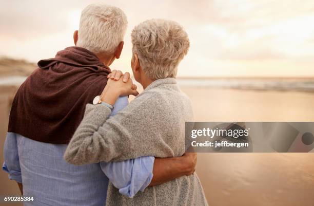 the sunset is an experience best shared - older couple hugging on beach stock pictures, royalty-free photos & images