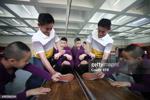 This photo taken on May 27, 2017 shows a teacher stretching a boy's legs during training at the Shenyang Peking Opera School in Shenyang, in China's...