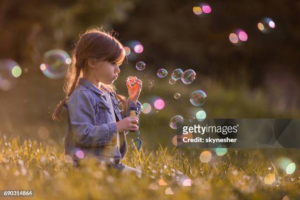 carina bambina che soffia bolle di sapone nel parco. - bubble wand foto e immagini stock