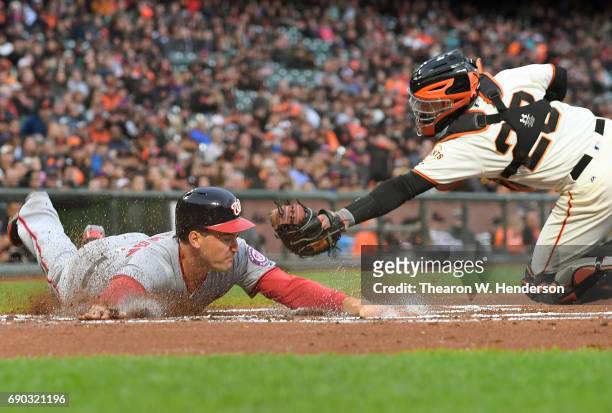 Ryan Zimmerman of the Washington Nationals scores sliding past the tag of Buster Posey of the San Francisco Giants in the top of the first inning at...