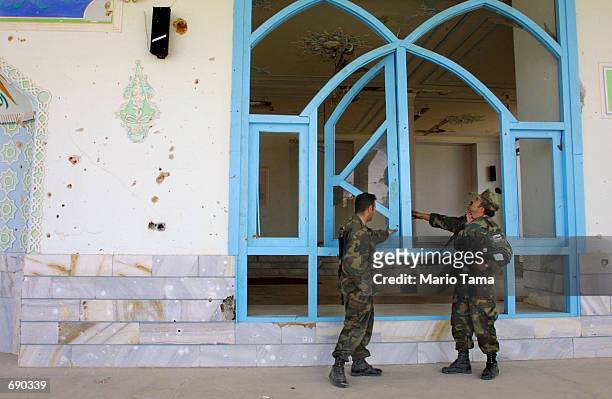 Jordanian Army Sgt. Mohammad S. Al-Ajarmeh and soldier Ahmadyhya Al-Mansory inspect a damaged mosque on the American military compound at Kandahar...