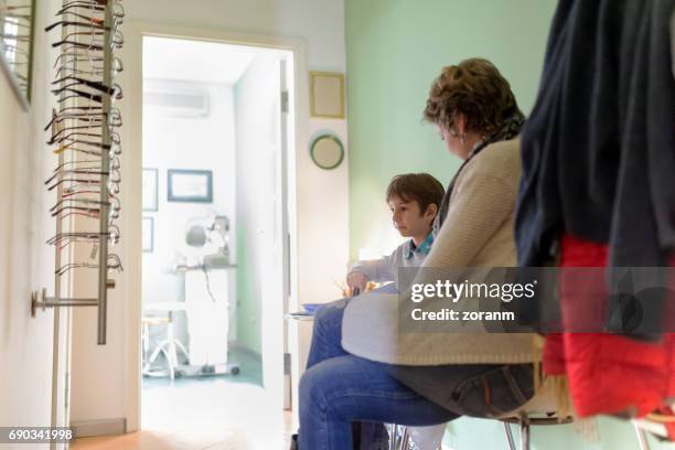 mother and son waiting in lobby - receiving treatment concerned stock pictures, royalty-free photos & images