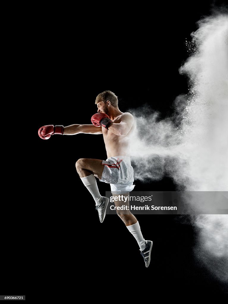 Young man boxing in air with white powder