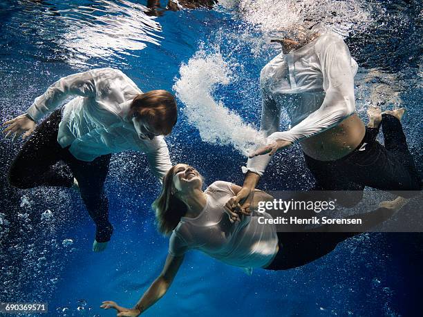 three people in the pool - man underwater stock pictures, royalty-free photos & images