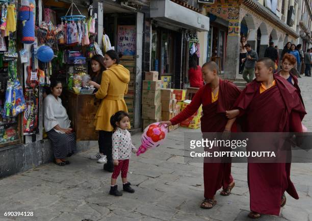 Bhutanse monks walk past shopkeepers in Thimpu on May 31, 2017. Japanese Princess Mako is scheduled to arrive on a nine-day official visit to Bhutan,...