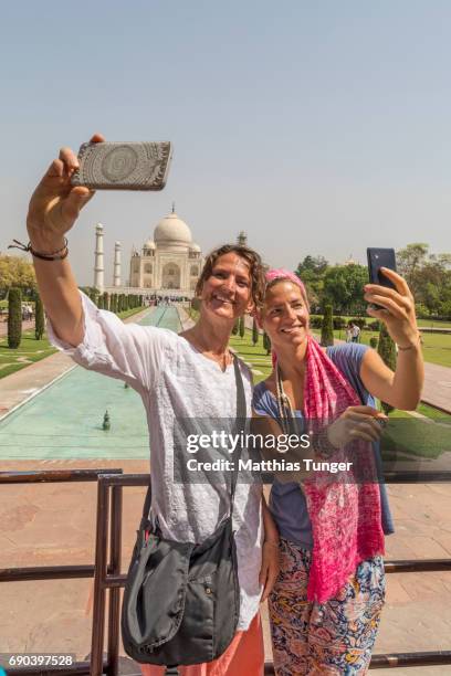 two women on a tour at the taj mahal playing with mobile phones - taj mahal selfie stock pictures, royalty-free photos & images