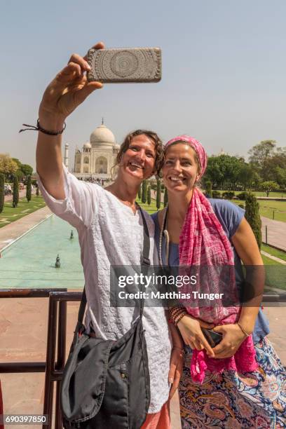 two women on a tour at the taj mahal playing with mobile phones - taj mahal selfie stock pictures, royalty-free photos & images