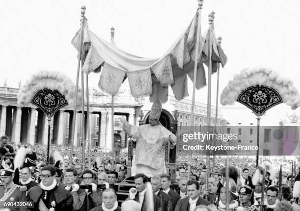 Le Pape Paul VI, coiffé de la mître et porté sur la Sedia Gestatoria, salué par des centaines de milliers de fidèles après la messe au cours de...
