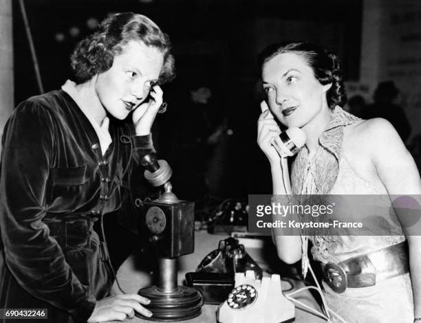 Jeunes filles utilisant un ancien et un nouveau modèle de téléphone pour en montrer l'évolution, à New York, Etats-Unis, le 20 octobre 1936.