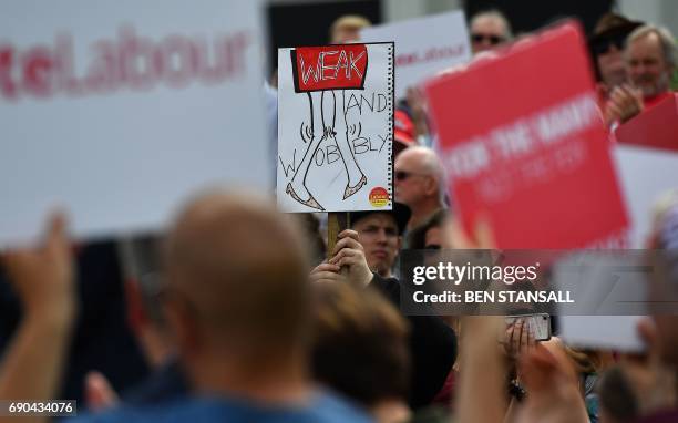 Supporters of Britain's main opposition Labour party hold a banner reading "Weak and Wobbly", referring to Britain's Prime Minister Theresa May, as...