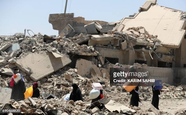Displaced Iraqis carry items as they evacuate from western Mosul's Zanjili neighbourhood as government forces advance in the area during their...