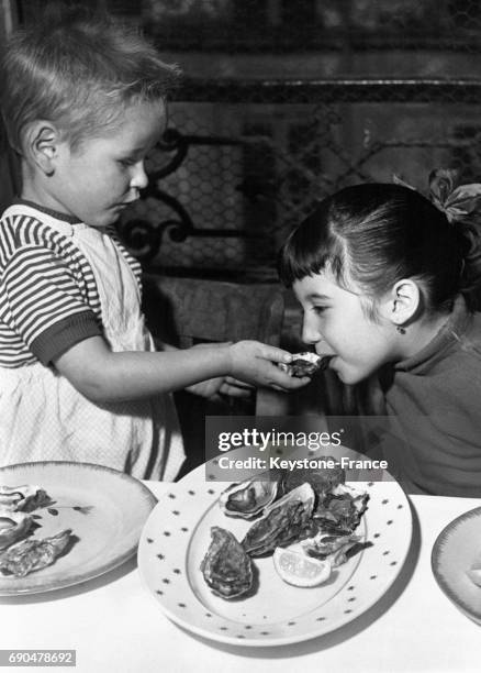 Un petit garçon tend une huître à sa soeur pour qu'elle la goûte le 29 août 1957.