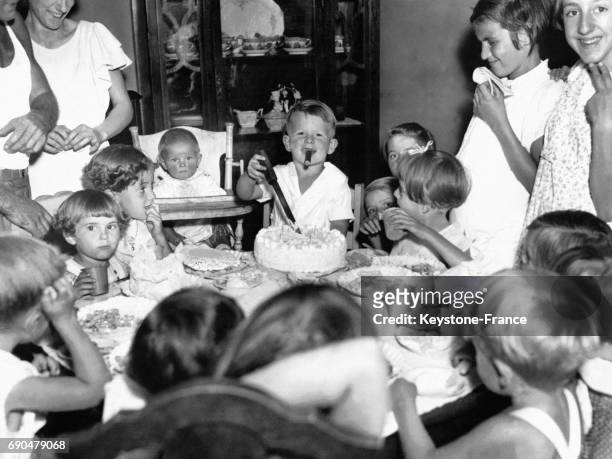 Un petit garçon de quatre ans, un cigare à la bouche, coupe un gâteau d'anniversaire entourés d'autres enfants le 29 juillet 1935 à New York City, NY.