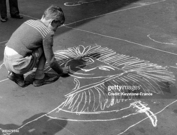 Un petit garçon dessine un lion à la craie sur le sol pendant les vacances d'été à Amsterdam, Pays-Bas.