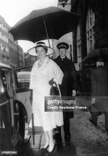 La bégum des Ismaéliens Aga Khan Yvette Labrousse quittant le palace l'hôtel Ritz, un portier la protégeant avec un parapluie, le 17 juin 1958,