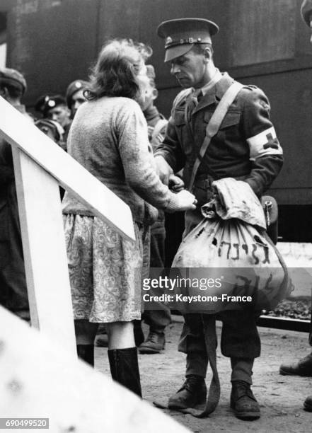 Un soldat britannique de la Croix Rouge aide une femme venant de Hambourg à porter ses valises à la gare de Kücknitz, Allemagne le 8 septembre 1947.