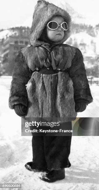 Portrait d'une petite fille chaudement vêtue d'un manteau en fourrure, capuche et lunettes de soleil, parée pour les températures hivernales, �à...