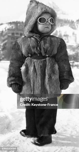 Portrait d'une petite fille chaudement vêtue d'un manteau en fourrure, capuche et lunettes de soleil, parée pour les températures hivernales, à...