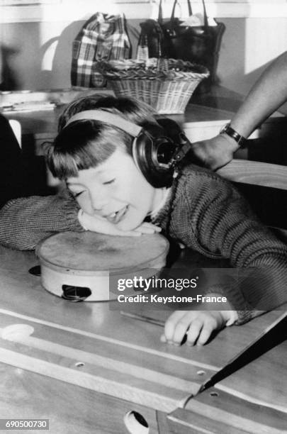 Cette petite fille sourde est heureuse d'écouter de la musique qui lui parvient des gros écouteurs, à l'Ecole pour les Sourds de Nottingham,...