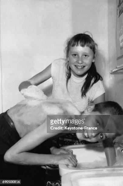 Deux des vainqueurs du concours de la propreté, le garçon se fait laver le dos par la jeune fille, à Paris, France le 7 juin 1957.