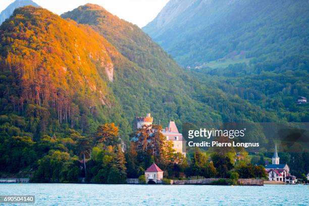 annecy lake - the château de duingt and the village of duingt located on a narrow peninsula with the alps in the backdrop - haute savoie stock-fotos und bilder