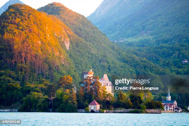 annecy lake - the château de duingt and the village of duingt located on a narrow peninsula with the alps in the backdrop - haute savoie stockfoto's en -beelden