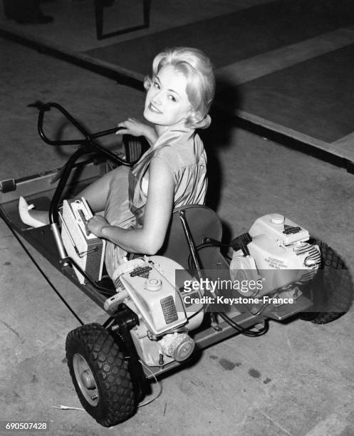 Jeune femme assise dans un karting à moteurs avec un poste de radio installé à côté d'elle, au Earls Court de Londres, Angleterre, Royaume-Uni, le 23...