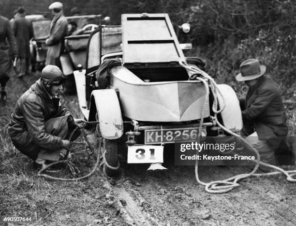 Des participants de la course reliant Oxford à Cambridge enroulent des cordes autour des pneus pour donner de l'adhérence aux roues qui patinent dans...