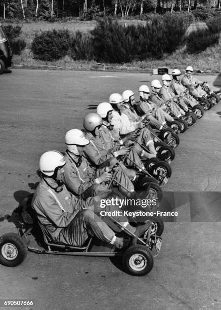 Pilotes portant casques et combinaisons installés au volant de leurs kartings à moteur au départ d'une course de démonstration, à Chertsey,...