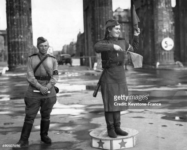 Policier et milicienne soviétique, fusil en bandoulière, faisant la circulation avec un petit drapeau sur un plot dans la zone d'occupation...