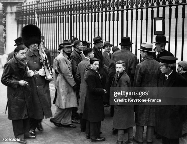 Une petite foule devant les grilles de Buckingham Palace pour lire le bulletin de santé affiché du Roi qui souffre de problèmes cardiaques le 19...