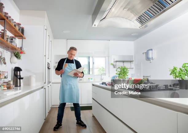 mid adult chef cooking in a modern kitchen - chef full length stock pictures, royalty-free photos & images