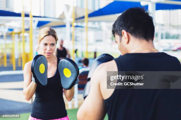 boxeador practicando con su entrenador personal femenino - boxercise fotografías e imágenes de stock