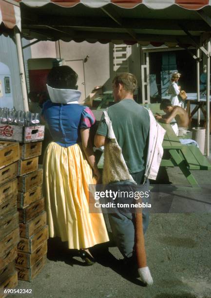 Two Disney character actors, dressed as Snow White and a fox, walk together on a backlot at Disneyland, Anaheim, California, August 1962.