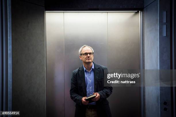 homme d’affaires sur un ascenseur d�’âge moyen - ascenseur interieur photos et images de collection