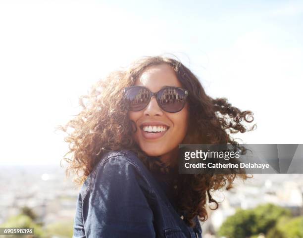 a young woman, wearing sun glasses, smiling in paris - shade stock pictures, royalty-free photos & images