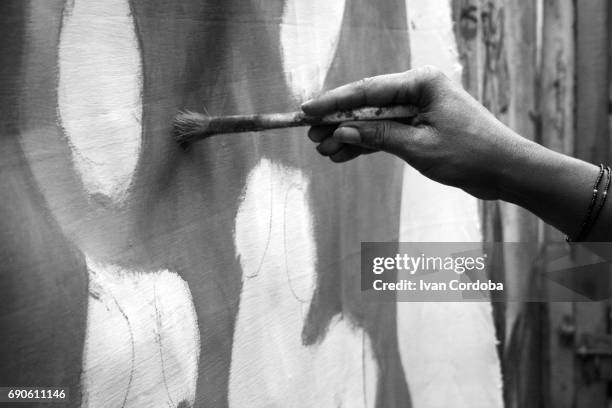 hand and paintbrush of african painter working out a canvas in bujumbura, burundi. - tribo africana oriental imagens e fotografias de stock