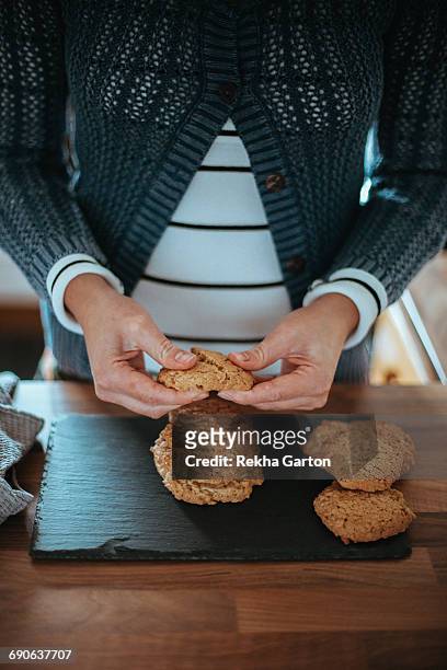 woman breaking a cookie in half - rekha garton stock-fotos und bilder