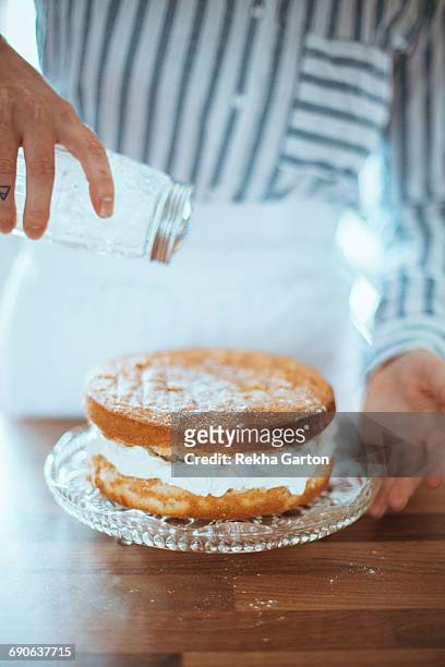 woman dusting a cake - rekha garton stock pictures, royalty-free photos & images