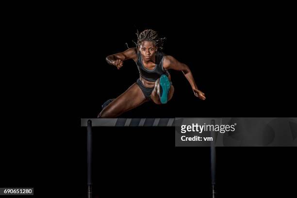 athlète sautant par-dessus un obstacle pendant la nuit - hurdling photos et images de collection
