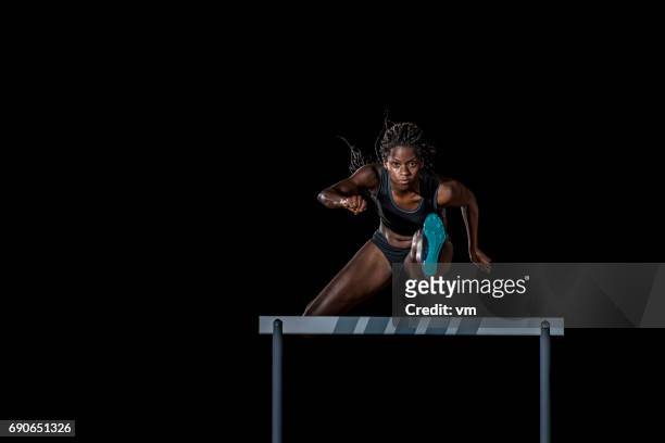 atleta femminile che salta su un ostacolo - posizione sportiva foto e immagini stock