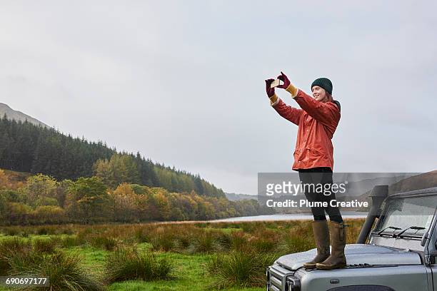 woman standing on car taking photo - photophone fotografías e imágenes de stock